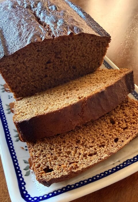 Sliced French spice bread (pain d'épices) loaf on a white platter with a blue dotted rim